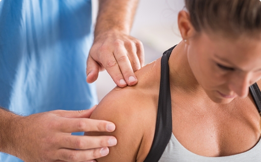 A chiropractor massaging a woman's shoulder